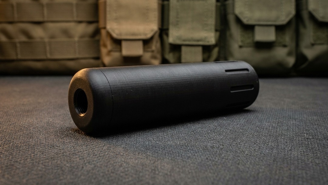 Full length side view of the black Mini Magna SD 3D printed airsoft moderator on a dark tactical bench